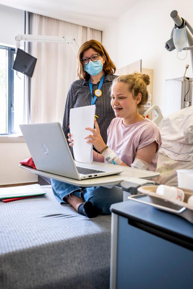 Leerkracht en leerlingen werken met de laptop in Ziekenhuisschool Antwerpen_
